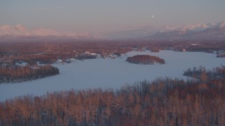 AK0001_2091 - 4K aerial stock footage snowy, wooded shore of Cottonwood Lake, Finger Lake, Wasilla, Alaska, twilight