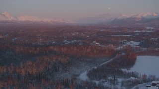 AK0001_2093 - 4K aerial stock footage over snow covered homes, Walby Lake, reveal mountains, Palmer, Alaska, twilight