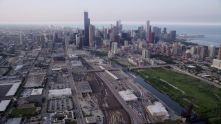 AX0001_076 - 4.8K aerial stock footage tiliting from train yards by the Chicago River, revealing downtown skyline on a hazy day, Downtown Chicago, Illinois