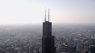 AX0001_082 - 4.8K aerial stock footage orbiting the top of Willis Tower in Downtown Chicago, on a hazy day, Illinois