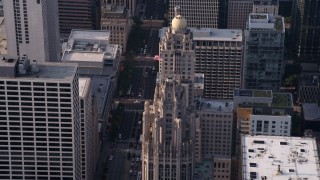 AX0001_118 - Aerial stock footage of 4.8K aerial  video approach flag flying at top of Tribune Tower in Downtown Chicago, Illinois