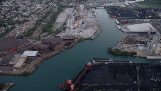 AX0001_167 - 4.8K aerial stock footage tilt from piles of petroleum coke by the Calumet River to reveal more industrial buildings, East Side Chicago, Illinois