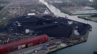 AX0001_169 - Aerial stock footage of 4.8K aerial  video approach petroleum coke piles by the Calumet River, East Side Chicago, Illinois