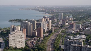 AX0002_094 - 4.8K aerial stock footage of following train tracks by Hyde Park apartment buildings, Chicago, Illinois