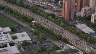 AX0003_020 - 4.8K aerial stock footage of tracking a commuter train passing by Hyde Park, at twilight, Chicago, Illinois