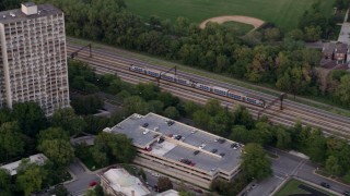 AX0003_021 - 4.8K aerial stock footage of a commuter train passing through Kenwood, Illinois, twilight