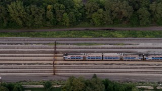 AX0003_023 - 4.8K aerial stock footage of tracking a commuter train traveling through Kenwood at twilight, Chicago, Illinois