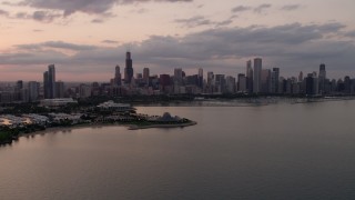 AX0003_029 - 4.8K aerial stock footage of Downtown Chicago skyline and the Adler Planetarium seen from Lake Michigan at sunset, Illinois