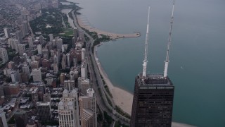 AX0003_052 - 4.8K aerial stock footage of flying over top of John Hancock Center, with a view of Lake Shore Drive at sunset, Downtown Chicago, Illinois