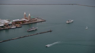 AX0003_062 - 4.8K aerial stock footage of ferries sailing by the end of Navy Pier, Chicago, Illinois, sunset