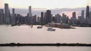 AX0003_065 - 4.8K aerial stock footage of the Downtown Chicago skyline and Navy Pier, revealing lighthouse with clouds at sunset, Illinois