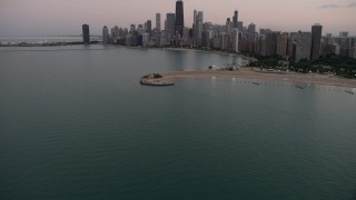 AX0003_072 - 4.8K aerial stock footage tilt from Lake Michigan, revealing North Avenue Beach and Downtown Chicago skyline, at twilight, Illinois