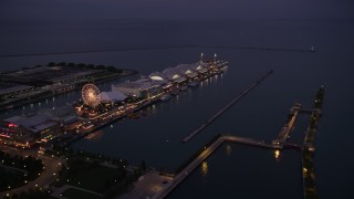 AX0003_122 - 4.8K aerial stock footage of flying by a Ferris wheel and rides on Navy Pier at twilight, Chicago, Illinois