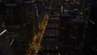 AX0003_135 - 4.8K aerial stock footage follow the Chicago River over bridges and tilt up, Downtown Chicago, Illinois, twilight