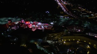 AX0004_007E - 5K aerial stock footage of approaching Universal Studios Hollywood at night, California