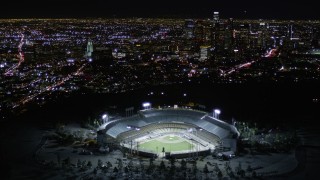 AX0004_034 - 5K aerial stock footage orbit Dodger Stadium and tilt to reveal Downtown Los Angeles at night, California
