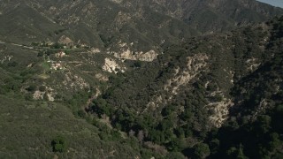 AX0005_003E - 5K aerial stock footage of flying through canyon and reveal hilltop homes in the San Gabriel Mountains of California