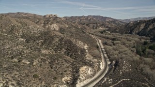 AX0005_021 - 5K aerial stock footage follow train tracks toward rock formation in Santa Clarita, California