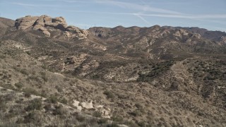 AX0005_031 - 5K stock footage aerial video fly over a mountain ridge to reveal rock formation in the Mojave Desert, California