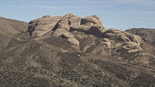 AX0005_032 - 5K aerial stock footage reveal and approach Mojave Desert rock formations in California
