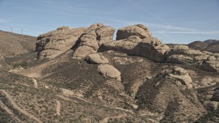 AX0005_033E - 5K aerial stock footage approach and fly over large Mojave Desert rock formations in California