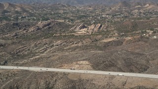 AX0005_036 - 5K stock footage aerial video approach Vasquez Rocks Park from the freeway in the Mojave Desert, California