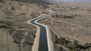 AX0005_061E - 5K stock footage aerial video of following the California Aqueduct by mountains in Mojave Desert, California
