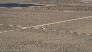 AX0005_073E - 5K aerial stock footage of tracking a big rig on a desert road in Antelope Valley, California