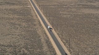 AX0005_075 - 5K aerial stock footage orbit a big rig and SUV on a desert road in Antelope Valley