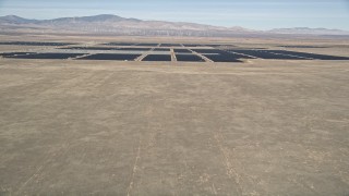 AX0005_100 - 5K aerial stock footage fly over desert hill to reveal vast solar energy array in Antelope Valley, California