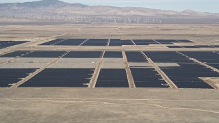 AX0005_102 - 5K stock footage aerial video fly low over desert hill and reveal solar array in Antelope Valley, California
