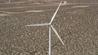 AX0005_135 - 5K aerial stock footage of a windmill with spinning blades in the Mojave Desert, California