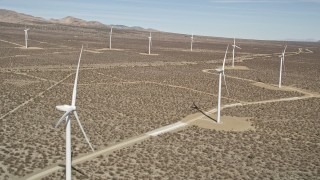 AX0005_139 - 5K aerial stock footage fly over a row of windmills at a desert wind farm in California