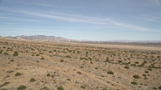 AX0006_004E - 5K aerial stock footage fly over desert plants toward wind farm in Antelope Valley, California