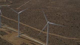 AX0006_011E - 5K aerial stock footage of orbiting a pair of windmills in the desert in Antelope Valley, California