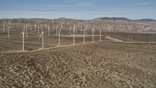 AX0006_013 - 5K stock footage aerial video approach a row of windmills at a wind farm in the Mojave Desert, California