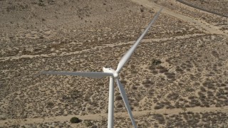AX0006_015 - 5K aerial stock footage tilt to bird's eye view of a windmill at a desert wind farm in California