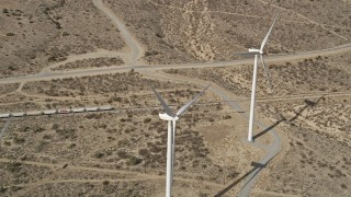 AX0006_016E - 5K aerial stock footage of flyby a trio of windmills at a wind farm in the Mojave Desert, California