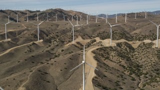 AX0006_022E - 5K aerial stock footage of approaching windmills at a desert wind energy farm in Antelope Valley, California