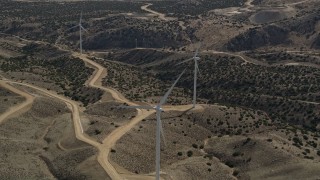 AX0006_025 - 5K stock footage aerial video orbit a single windmill at a desert wind farm in the Mojave Desert, California