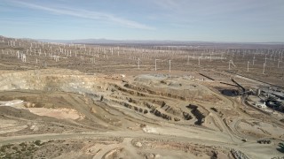 AX0006_032E - 5K aerial stock footage orbit pit of desert quarry near windmills in Antelope Valley, California