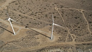 AX0006_040 - 5K aerial stock footage tilt to a bird's eye view of a pair of windmills in the Mojave Desert, California