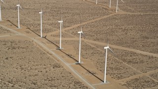 AX0006_050 - 5K aerial stock footage fly over a row of windmills at a wind farm in the California desert