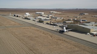 AX0006_055E - 5K stock footage aerial video pan to airliner by hangar at Mojave Air and Space Port in California