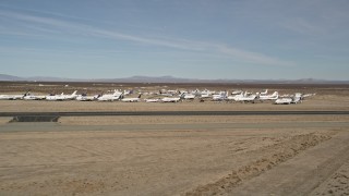 AX0006_057 - 5K aerial stock footage of a low altitude orbit of planes at an aircraft boneyard in the desert, Mojave Air and Space Port, California