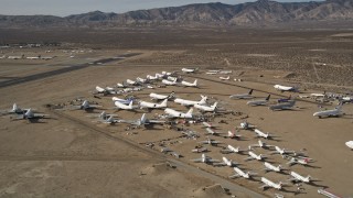 AX0006_058E - 5K stock footage aerial video orbit low around various jet airplanes at an aircraft boneyard in the desert, Mojave Air and Space Port, California