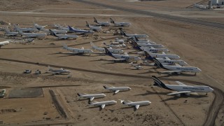 AX0006_064E - 5K stock footage aerial video orbit a group of aircraft at a boneyard in the Mojave Desert, California