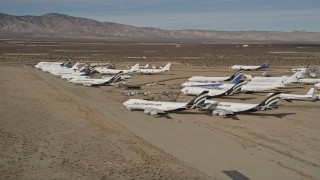 AX0006_068 - 5K aerial stock footage of jet aircraft at a desert boneyard in California's Mojave Desert