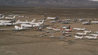 AX0006_072 - 5K aerial stock footage orbit large and small jets at a desert aircraft boneyard in Mojave Air and Space Port, California 