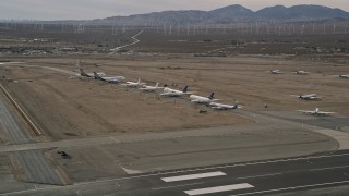 AX0006_078 - 5K aerial stock footage orbit large jet aircraft in a row at a desert boneyard, Mojave Air and Space Port, California